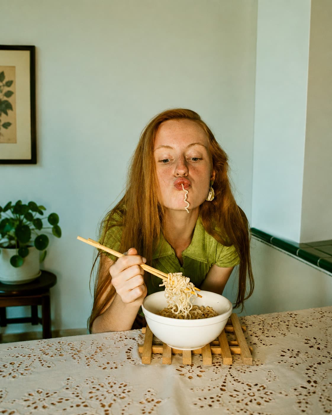 Una ragazza con i capelli rossi mangia con le bacchette una ciotola di noodles senza glutine